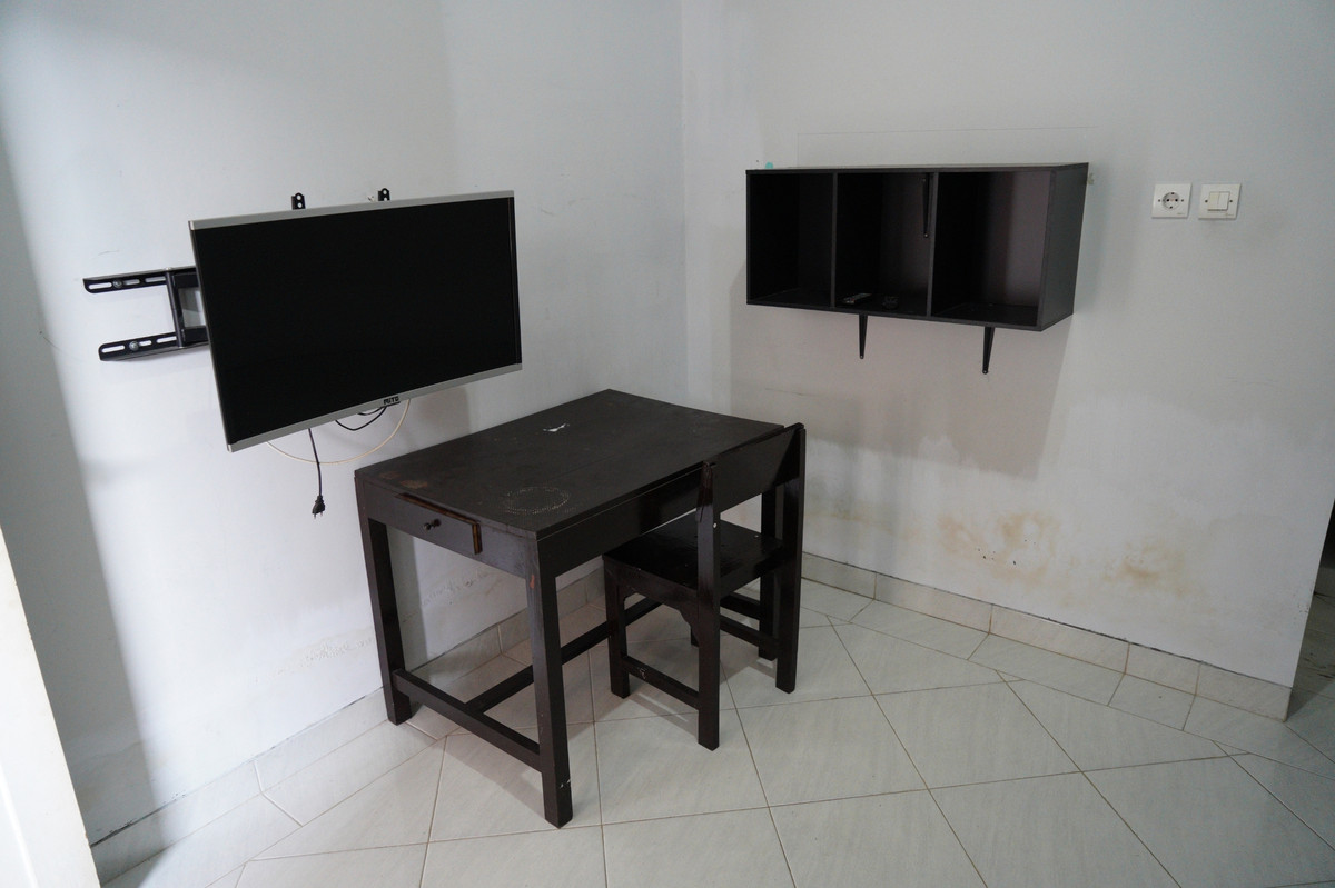 Meja belajar, kursi, TV, dan rak dinding di kamar